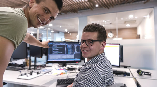 Zwei Männer vor einem PC-Arbeitsplatz